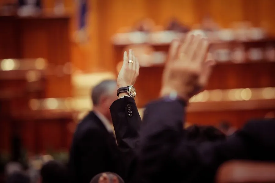 hands voting in an official parliamentary setting